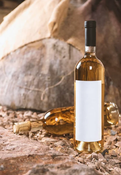 Glass and bottle of white wine in the wine cellar. Bottle with a label-preparation for designers