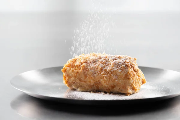 Napoleon cake with icing sugar on black background . Decorating napoleon cake with powdered sugar.