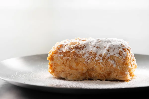 Napoleon cake with icing sugar on black background . Decorating napoleon cake with powdered sugar.