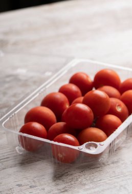 Tahta masadaki plastik kaplarda kiraz domatesleri.