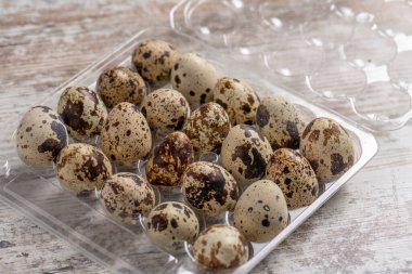 Tahta bir masada plastik kaplarda bıldırcın yumurtaları.