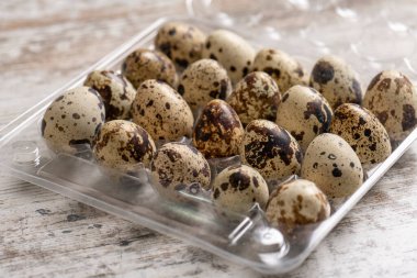 Tahta bir masada plastik kaplarda bıldırcın yumurtaları.