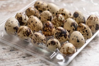 Tahta bir masada plastik kaplarda bıldırcın yumurtaları.