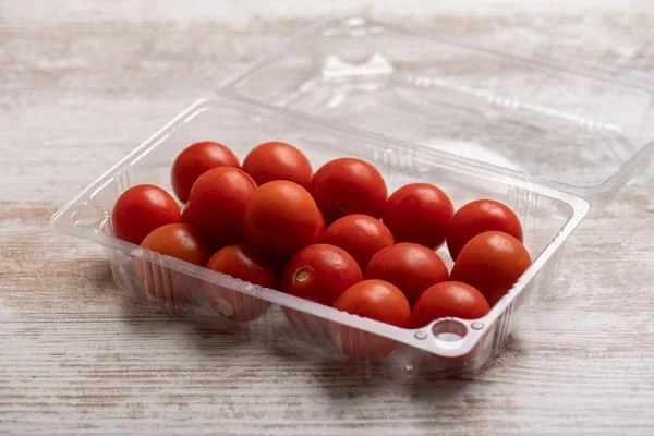 Tahta masadaki plastik kaplarda kiraz domatesleri.