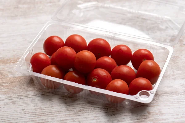 Tahta masadaki plastik kaplarda kiraz domatesleri.