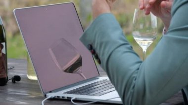 Man holds an online meeting in nature with a glass of wine