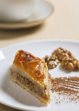 Geleneksel Arap tatlı baklavası ve bir fincan kahve ya da çayla birlikte beyaz tabakta ceviz. Ev yapımı fındıklı ve ballı baklava..