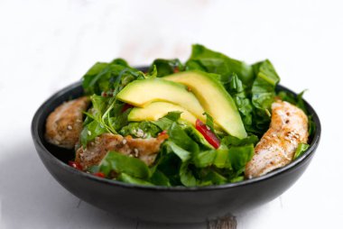 Siyah kasede avokadolu tavuk salatası. Sağlıklı yemek.