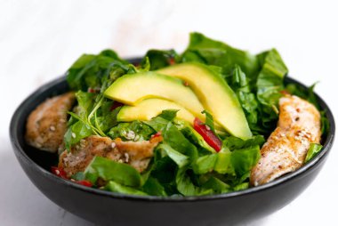 Sağlıklı sebze salatası, kızarmış tavuk, avokado, biber ve beyaz tabakta yaprak salatası..