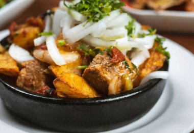 Beef stew with potatoes, carrots and herbs on black background with copy