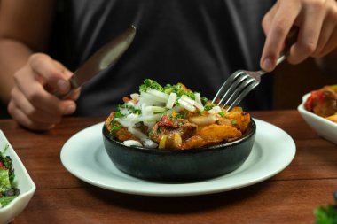 Man eating Beef stew with potatoes, carrots and herbs on black background with copy