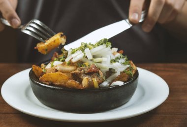Man eating Beef stew with potatoes, carrots and herbs on black background with copy
