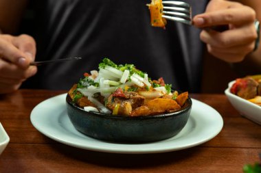 Man eating Beef stew with potatoes, carrots and herbs on black background with copy