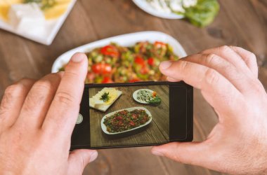 Yemek blogcusu akıllı telefon kullanarak fotoğraf çekiyor. Mans elleri geleneksel doğu yemeklerini telefonla çekiyor. Öğle ya da akşam yemeği. Sosyal medya ve blog için. Sağlıklı yemek.