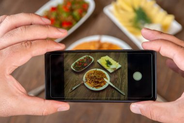 Yemek blogcusu akıllı telefon kullanarak fotoğraf çekiyor. Mans elleri geleneksel yemeklerin fotoğrafını çekiyor. Öğle ya da akşam yemeği. Sığır stroganoff. Sosyal medya ve blog için. Üst görünüm cep telefonu.