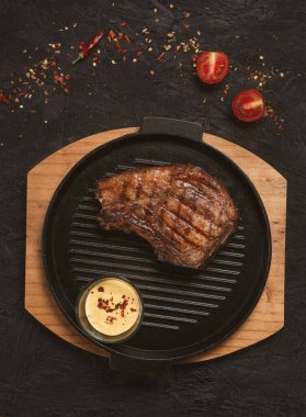 pork steak with vegetables in a black iron pan , top view.