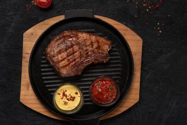 pork steak with vegetables in a black iron pan , top view.