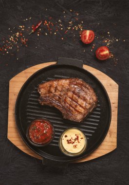 pork steak with vegetables in a black iron pan , top view.