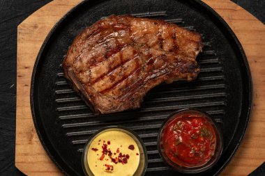 pork steak with vegetables in a black iron pan , top view.