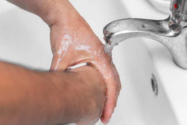man washes his hands in the bathroom.The best protection against corona virus infection.Corona Virus pandemic protection by cleaning hands frequently.