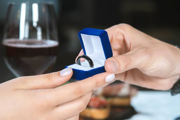 Male hands with blue velvet box containing payments smart ring. Man gives a woman payments smart ring.  Romantic dinner. Valentine day