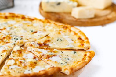 Tahta üzerinde dört peynirli pizza ve beyaz ahşap bir masada İtalyan pizzası için taze malzemeler. .