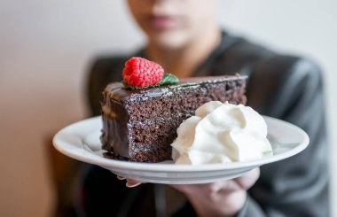 Çikolatalı pasta ve krem şanti gösteren bir kadın.