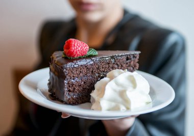 Çikolatalı pasta ve krem şanti gösteren bir kadın.