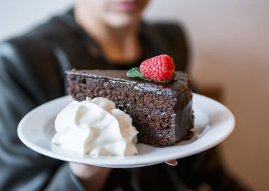 Çikolatalı pasta ve krem şanti gösteren bir kadın.