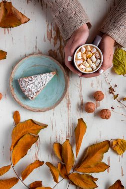 Pasta, ceviz ve dağınık yapraklarla dolu eski püskü bir masada elinde lokum tutan kadınların üst görüntüsü.