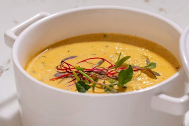 Balkabağı kremalı çorba seramik kapaklı otlarla servis edilir.