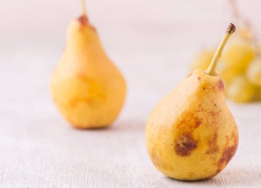 Beyaz masada servis edilen olgun sarı armutlar, sağlıklı yiyecekler.