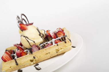 Dondurma, çilek ve çikolatayla servis edilen waffle 'ın yakın görüntüsü