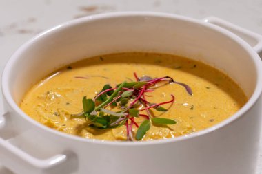 Balkabağı kremalı çorba seramik kapaklı otlarla servis edilir.