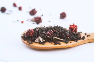 beyaz arka plan üzerinde izole ahşap bir kaşık üzerinde ahududu ile aromatik siyah kuru çay