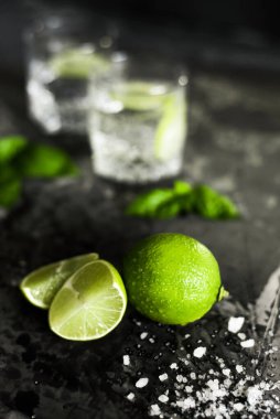 Ön planda limon meyvesi ve arka planda sıvı bardaklar.