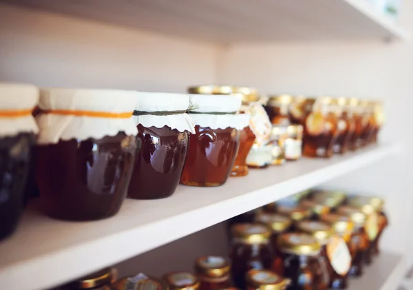 Estante con miel casera y mermelada — Foto de Stock