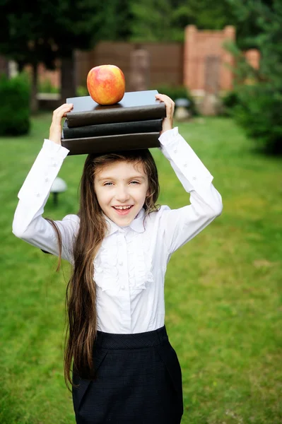 Ung flicka i skoluniform leker med böcker — Stockfoto