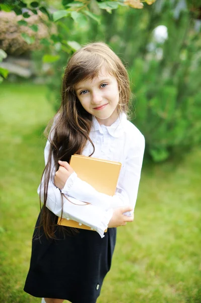 Junges Mädchen in Schuluniform hält ein Buch in der Hand — Stockfoto