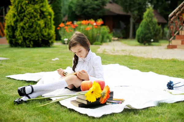 Leuk meisje in schooluniform lezen van een boek — Stockfoto