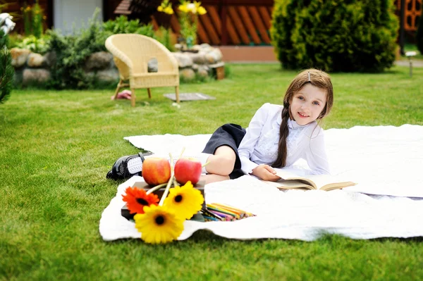 Jolie fille en uniforme scolaire lisant un livre — Photo