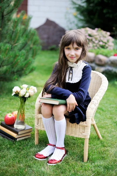 Jolie fille en uniforme scolaire tenant un livre — Photo