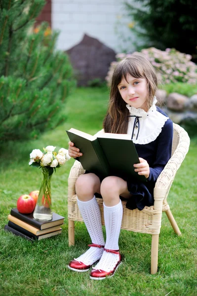Cute girl in school uniform reading a book — Stock Photo, Image
