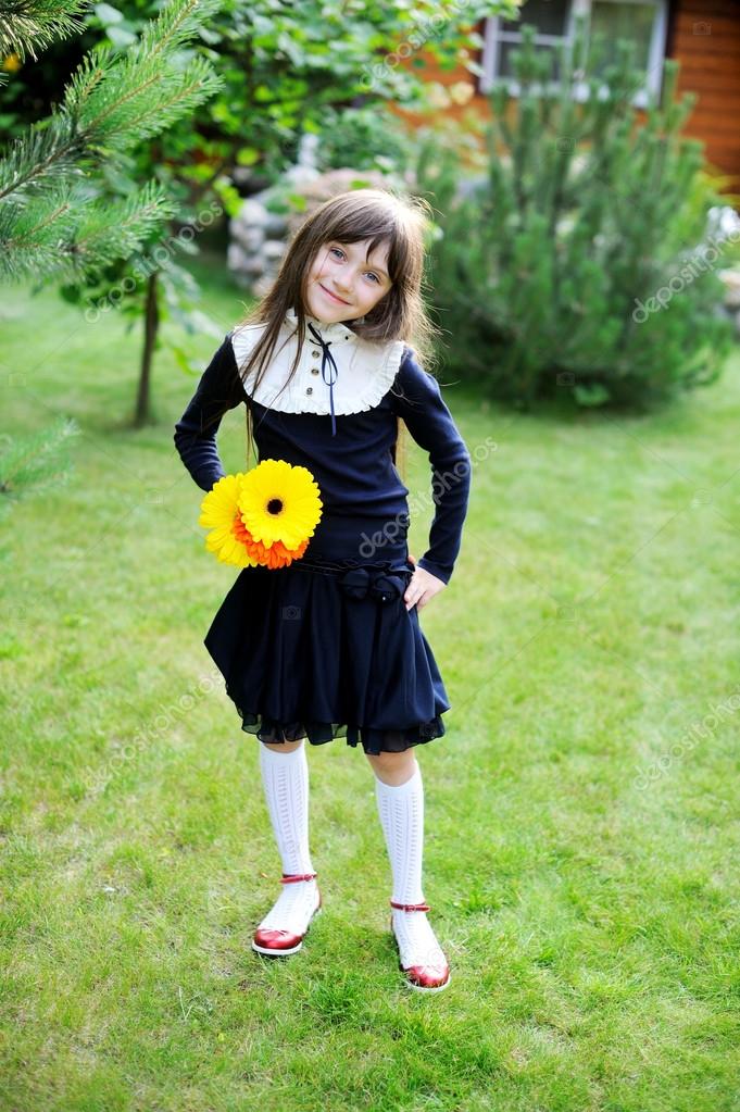 Young girl in school uniform posing with flowers — Stock Photo
