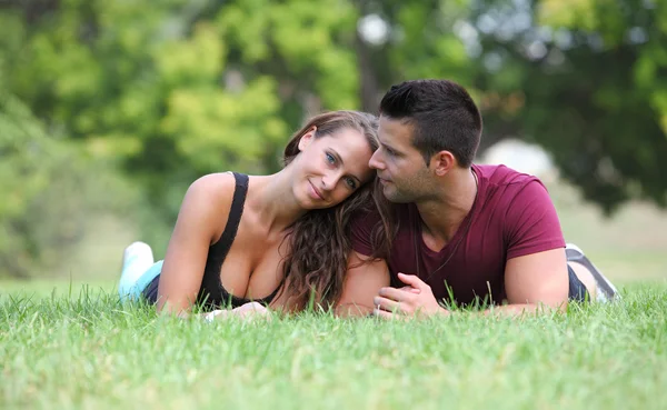 Retrato de una joven pareja acostada en la hierba — Foto de Stock