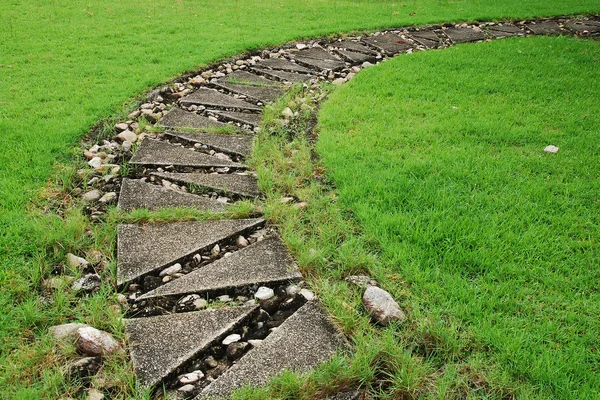 Camino de piedra a través de un césped verde cubierto de hierba — Foto de Stock