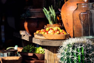 Meyve pazarında güzel bir vitrin. Ahşap tepside kırmızı elmalar, kaktüsler ve kil vazolar.