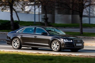 Moskova; Rusya - 14 Ekim 2021: Siyah Audi A8 sıcak bir sonbahar gününde bir parkın arka planına doğru hızla ilerliyor
