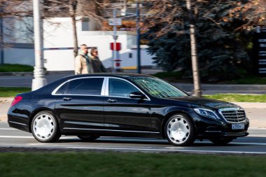 Moskova; Rusya - 14 Ekim 2021: Siyah Mercedes S-Sınıfı Maybach, sıcak bir sonbahar gününde bir parkın arka planına doğru hızla sürüyor.