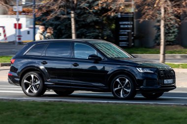 Moskova; Rusya - 14 Ekim 2021: Siyah Audi Q7 sıcak bir sonbahar gününde bir parkın arka planına doğru hızla ilerliyor